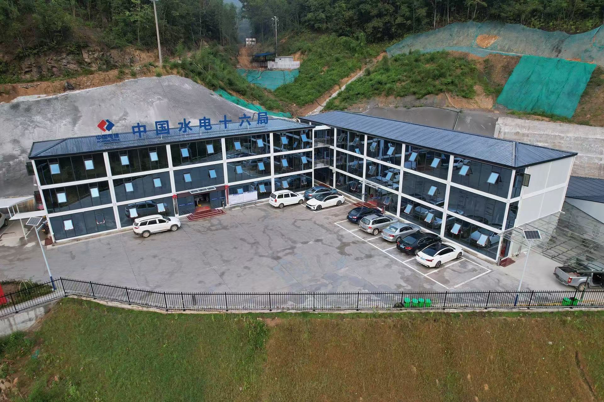 Large modular construction site office complex with glass facade and parking area in a project environment