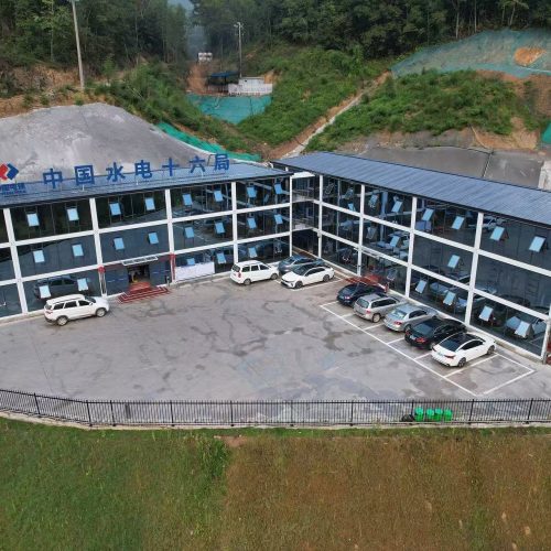 Large modular construction site office complex with glass facade and parking area in a project environment